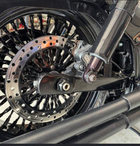 Close-up of the LawlessCC Harley swing arm installed on a Softail showing rear wheel and suspension clearance.